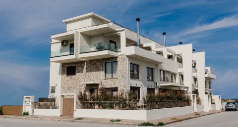 Συγκρότημα κατοικιών στη Νεάπολη Λάρισας: γωνιακή όψη με πέτρινη επένδυση και λευκούς εξώστες